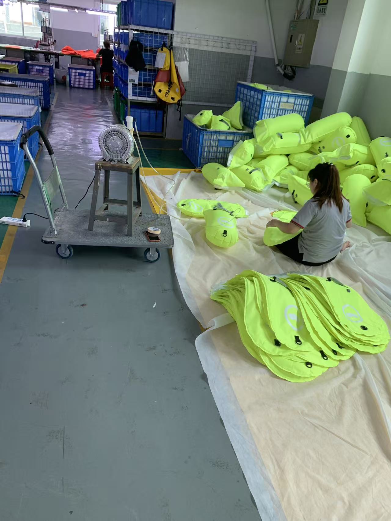 Worker inflating high-visibility swim buoys with an air blower